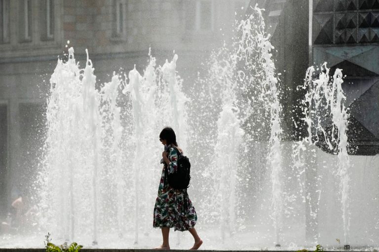 A woman walks past a fountain on a hot summer day in Berlin, Germany, Sunday, June 19, 2022. People flocked to parks and pools across Western Europe on Saturday for a bit of respite from an early heat wave. In Germany, where highs of 38 C (100.4 F) were expected, the health minister urged vulnerable groups to stay hydrated.