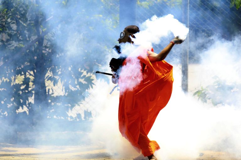 A man throws back a tear gas canister after it was fired by police to disperse protesters in Colombo, Sri Lanka, Saturday, July 9, 2022. Sri Lankan protesters demanding that President Gotabaya Rajapaksa resign forced their way into his official residence on Saturday, a local television report said, as thousands of people took to the streets in the capital decrying the island nation's worst economic crisis in recent memory. 