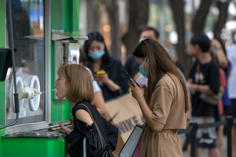 A woman has her throat swabbed for a COVID-19 test at a coronavirus testing site in Beijing, Saturday, Aug. 6, 2022.