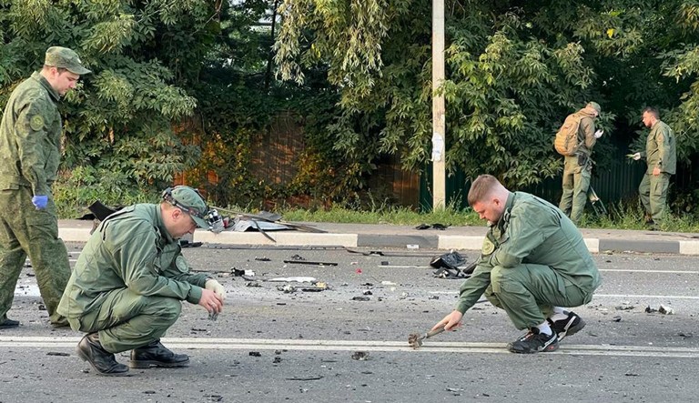 In this handout photo taken from video released by Investigative Committee of Russia on Aug. 21,  investigators work on the site of explosion of a car driven by Daria Dugina outside Moscow. 