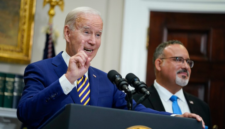 President Joe Biden speaks about student loan debt forgiveness in the Roosevelt Room of the White House, Wednesday, Aug. 24, 2022, in Washington. Education Secretary Miguel Cardona listens at right.