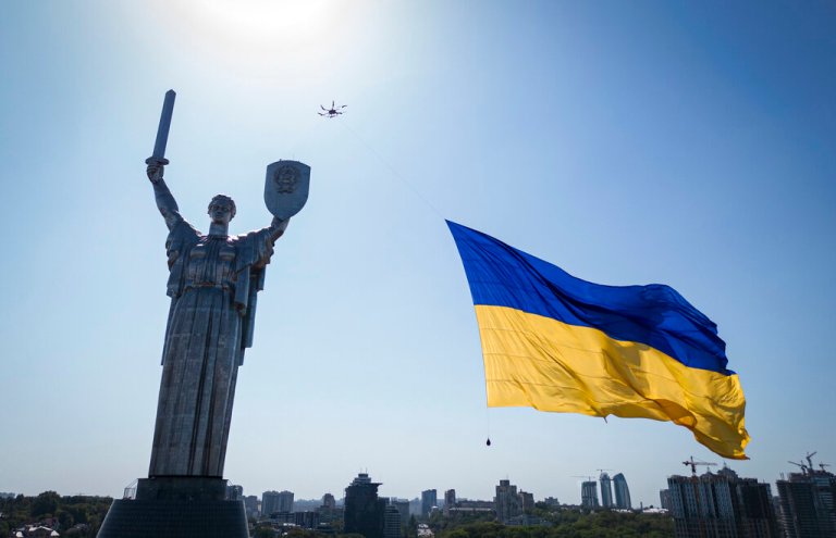 A drone carries a big national flag in front of Ukraine's the Motherland Monument. in Kyiv, Ukraine, Aug. 24, 2022.