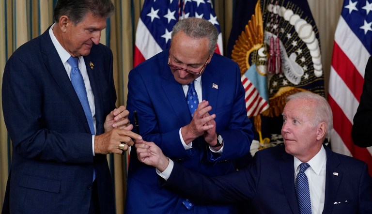 President Joe Biden hands the pen he used to sign the Democrats' landmark climate change and healthcare bill to Sen. Joe Manchin, as Senate Majority Leader Chuck Schumer watches in the State Dining Room of the White House in Washington, Aug. 16, 2022. 