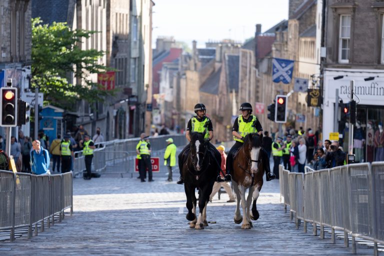 Police are seen on the Royal Mile as Edinburgh prepares for thousands of well-wishers to line streets of the city when the Queen's coffin is brought to the Palace of Holyroodhouse, Edinburgh, Scotland, Saturday, Sept. 10, 2022. (AP Photo/Jon Super)