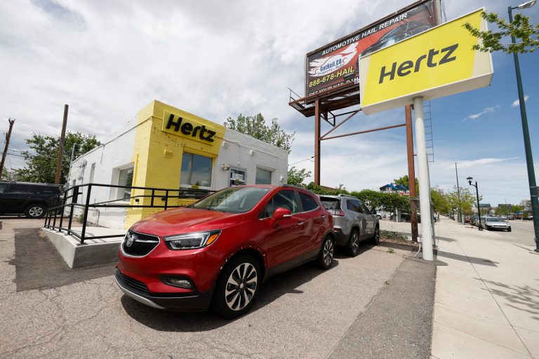 Rental vehicles are parked outside a closed Hertz car rental office in south Denver.