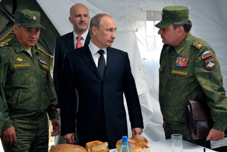 Russian President Vladimir Putin, center, listens to Deputy Defense Minister Dmitry Bulgakov, right, as Defense Minister Sergei Shoigu, left, and Gov. of Baikal region Konstantin Ilkovsky, background, observe military exercises near the Baikal Lake. 