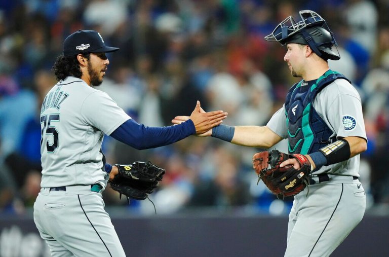 Seattle Mariners relief pitcher Andres Munoz (75) and catcher Cal Raleigh, right, celebrate after defeating the Toronto Blue Jays in Game 1 in an AL wild-card baseball playoff series in Toronto on Friday, Oct. 7, 2022. 