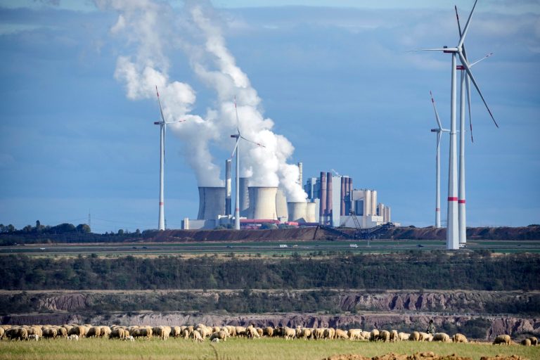 A flock of sheep graze in front of a coal-fired power plant at the Garzweiler open-cast coal mine near Lutzerath, western Germany, Sunday Oct. 16, 2022. The abandoned village of Luetzerath will be the latest village to disappear as coal mining at the Garzweiler mine expands. 