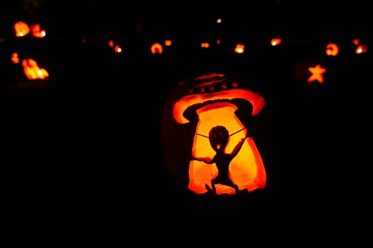 A jack-o'-lantern featuring a UFO and an alien is seen next to other decorated pumpkins at Ladew Topiary Gardens, Friday, Oct. 21, 2022, in Monkton, Md.