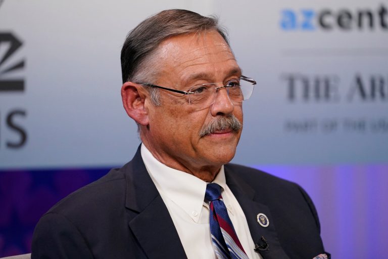 Arizona secretary of state GOP candidate Mark Finchem listens to instructions prior to debating Democratic challenger Adrian Fontes Thursday, Sept. 22, 2022, in Phoenix. 
