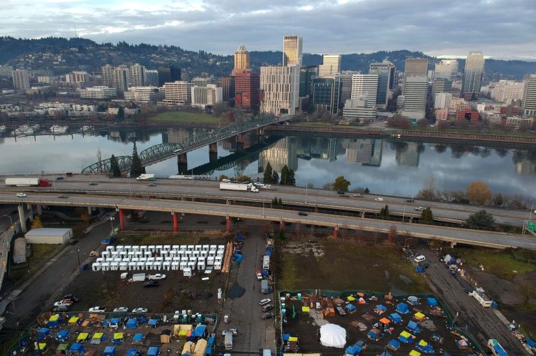 Tents housing people experiencing homelessness are set up on a vacant parking lot in Portland, Ore.