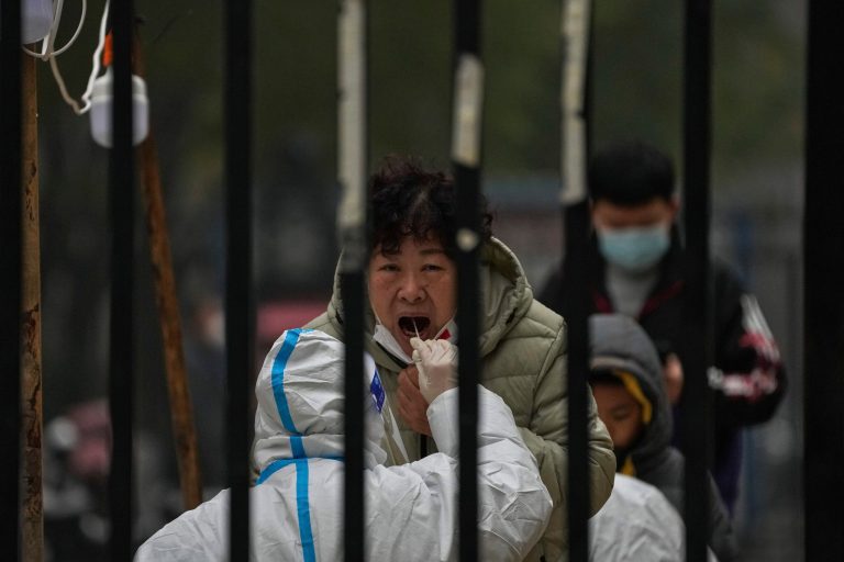 A woman has her routine COVID-19 test at a coronavirus testing site setup inside a residential compound in Beijing, Thursday, Nov. 24, 2022. China is expanding lockdowns, including in a central city where factory workers clashed this week with police, as its number of COVID-19 cases hit a daily record.