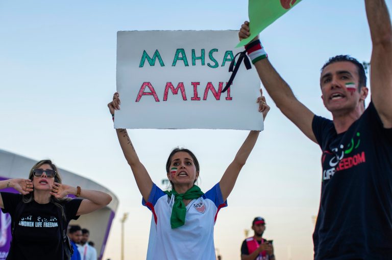 A woman holds up a sign reading Mahsa Amini, a woman who died while in police custody in Iran at the age of 22, during a protest after the World Cup group B soccer match between Wales and Iran, at the Ahmad Bin Ali Stadium Al Rayyan, Qatar, Friday, Nov. 25, 2022. 