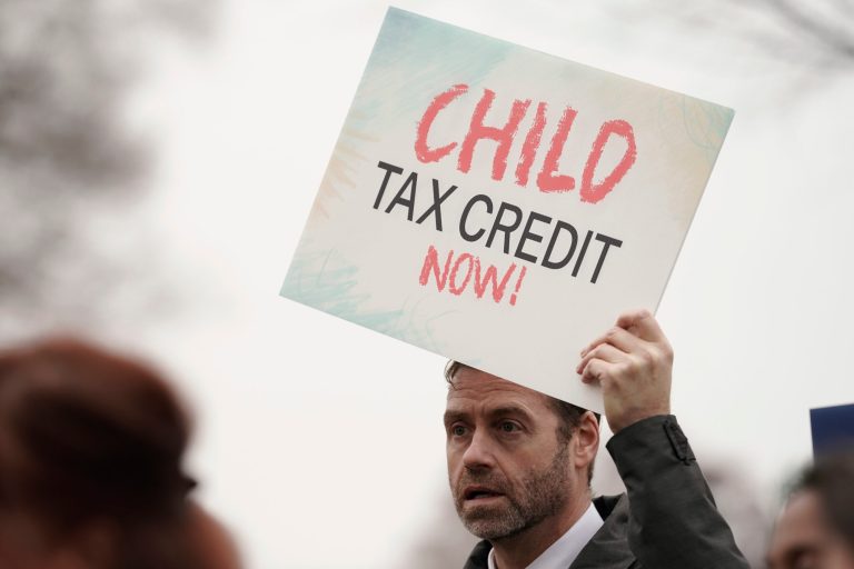 A man holds a sign during a news conference on the child tax credit, Wednesday, Dec. 7, 2022, on Capitol Hill in Washington.