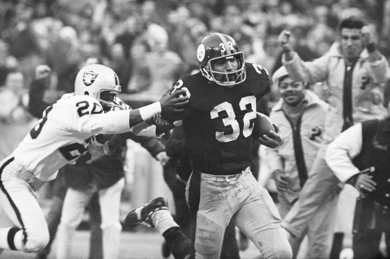 Pittsburgh Steelers' Franco Harris (32) eludes a tackle by Oakland Raiders' Jimmy Warren as he runs 42-yards for a touchdown after catching a deflected pass during an AFC Divisional NFL football playoff game in Pittsburgh on Dec. 23, 1972.