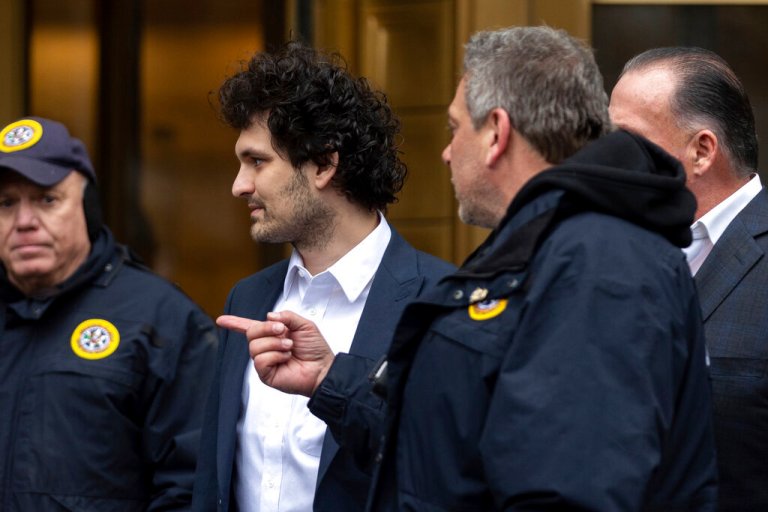 FTX founder Sam Bankman-Fried, center, is escorted to his car from the U.S. District Court in Manhattan, Thursday, Dec. 22, 2022, in New York. 