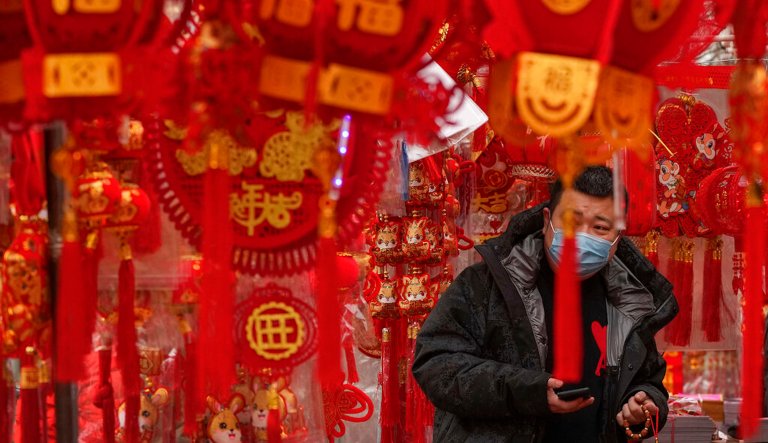 A man wearing a face mask shops for Chinese Lunar New Year decorations at a pavement store in Beijing, Saturday, Jan. 7, 2023. China has suspended or closed the social media accounts of more than 1,000 critics of the government's policies on the COVID-19 outbreak, as the country moves to further open up.