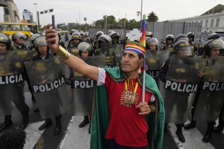 A demonstrator takes a selfie in front of a line of police in riot gear during a march against Peruvian President Dina Boluarte in Lima, Peru, Tuesday, Jan. 17, 2023.