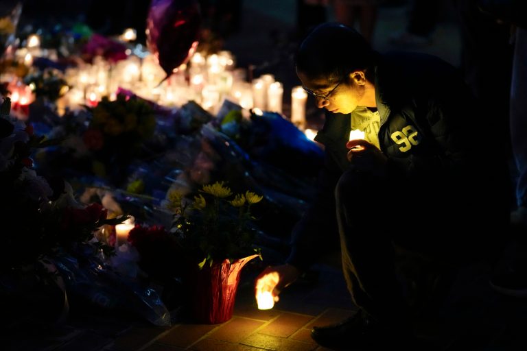 A man sets down a candle during a vigil outside Monterey Park City Hall, blocks from the Star Ballroom Dance Studio, on Tuesday, Jan. 24, 2023, in Monterey Park, California. A gunman killed multiple people at the ballroom dance studio late Saturday amid Lunar New Year's celebrations in the predominantly Asian American community.