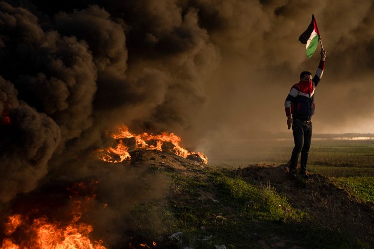 Palestinians burn tires and wave the national flag during a protest against Israeli military raid in the West Bank city of Jenin, along the border fence with Israel, in east of Gaza City, Thursday, Jan. 26, 2023.
