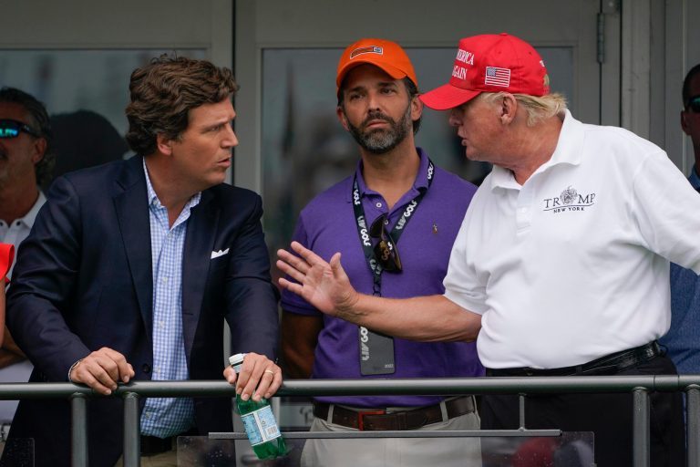 Former President Donald Trump, right, talks with Donald Trump Jr., center, and Tucker Carlson at the 16th tee during the final round of the Bedminster Invitational LIV Golf tournament in Bedminster, N.J., July 31, 2022. 