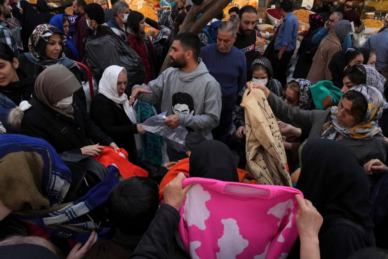 A street vendor sells clothes at the old grand bazaar of Tehran, Iran, Sunday, Feb. 26, 2023. Iran's currency fell to a new record low on Sunday, plunging to 600,000 to the dollar for the first time as the effects of nationwide anti-government protests and the breakdown of the 2015 nuclear deal continued to roil the economy. 