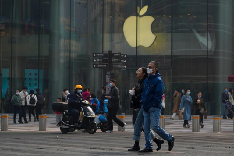 People wearing face masks walk by an Apple store at a tourist shopping street in Beijing, Sunday, March 5, 2023. China's government announced plans for a consumer-led revival of the struggling economy as its legislature opened a session Sunday that will tighten President Xi Jinping's control over business and society.