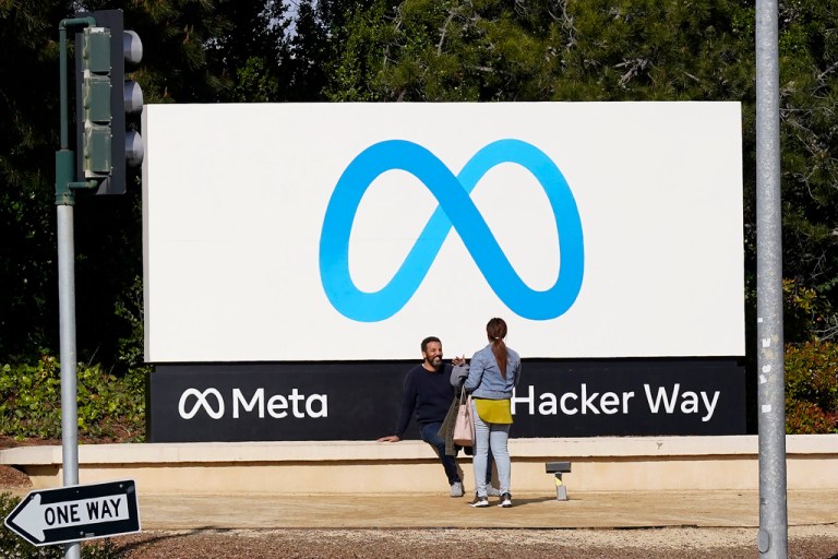 People talk near a Meta sign outside of the company's headquarters in Menlo Park, Calif., Tuesday, March 7, 2023. Facebookâs parent Meta will slash another 10,000 jobs and will not fill 5,000 open positions as the social media pioneer cuts costs. 