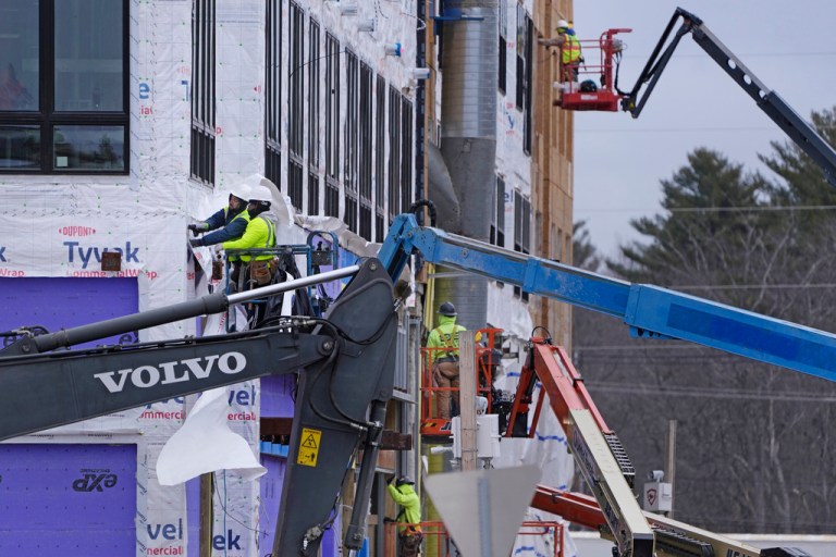 Construction workers prepare the facade of a building for sheathing at Tuscan Village, a mixed retail, commercial and residential complex currently under construction, Monday, March 13, 2023, in Salem, N.H. 