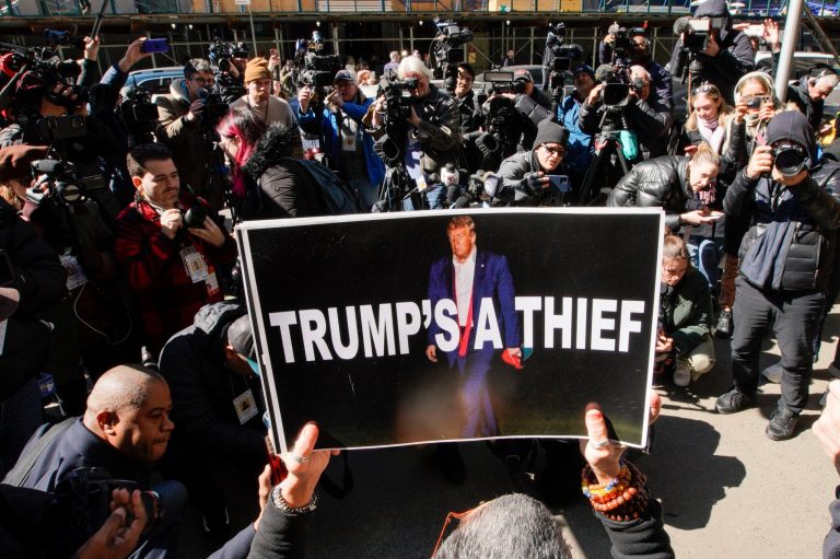 A woman holds up a poster as part of a protest in front of the courthouse ahead of former President Donald Trump's anticipated indictment on Monday, March 20, 2023, in New York. 