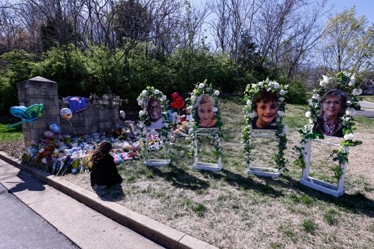 A woman prays near the likeness of four of the victims as she visits a memorial at the entrance to The Covenant School on Wednesday, March 29, 2023, in Nashville, Tennessee. 