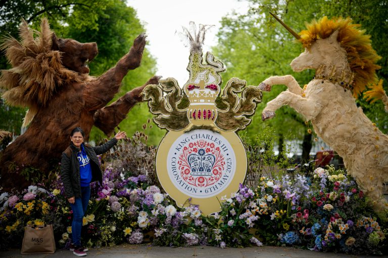 A woman poses next to an art installation celebrating the Coronation of King Charles III in London, Thursday, May 4, 2023. The Coronation of King Charles III will take place at Westminster Abbey on May 6.