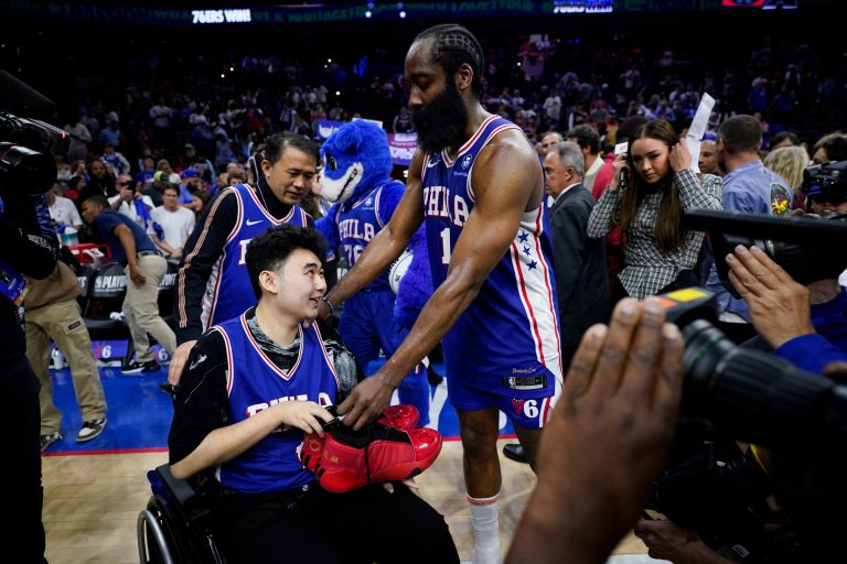 Philadelphia 76ers' James Harden gives his sneakers to John Hao after Game 4 in an NBA basketball Eastern Conference semifinals playoff series, Sunday, May 7, 2023, in Philadelphia. Harden invited Hao, a student severely wounded in a Feb. 13 mass shooting at Michigan State University, to view the game.