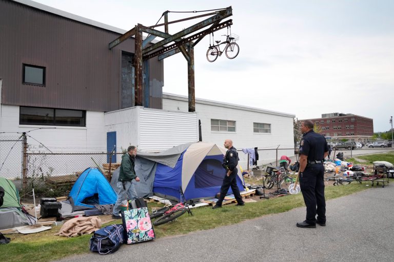 Police officers speak to a man at a homeless encampment, Tuesday, May 16, 2023, in Portland, Maine.  Maine's largest city started removing a large encampment as it grapples with homelessness and packed shelters.  