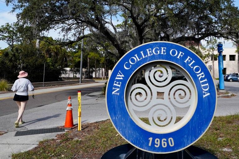 A student makes her way past the sign at New College of Florida, Jan. 20, 2023, in Sarasota, Florida. The New College of Florida trustees dominated by conservatives appointed by Gov. Ron DeSantis chose a new mascot on Thursday, June 1, 2023, for the Sarasota school: the Mighty Banyans. The tree mascot will replace one that has been in use since 1997, which is the mathematical formulation of the Null Set.