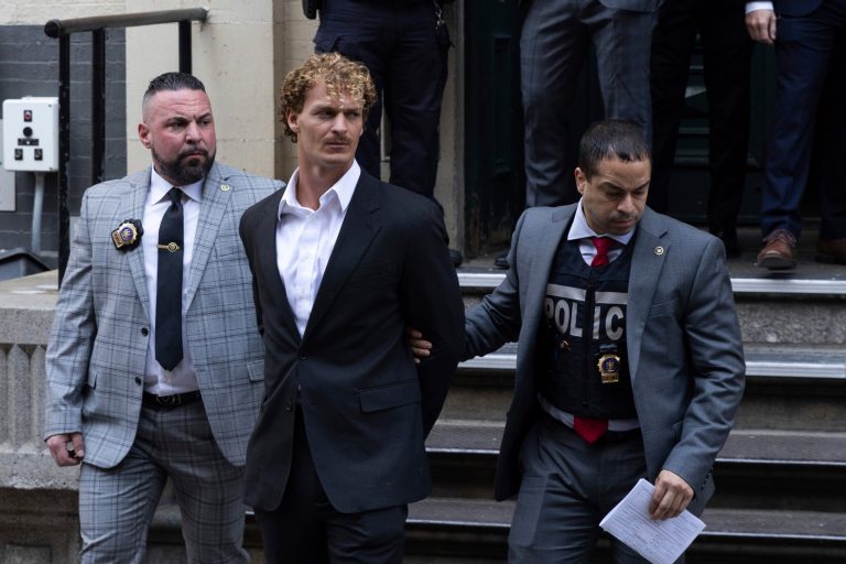 FILE - Daniel Penny, center, is walked by New York Police Department detectives out of the 5th Precinct, May 12, 2023, in New York. (AP Photo/Jeenah Moon, File)
