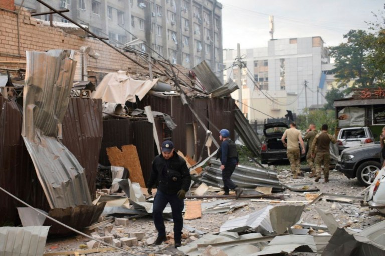 In this photo provided by the National Police of Ukraine, a police officer and a rescue worker walk in front of a restaurant RIA Pizza destroyed by a Russian attack in Kramatorsk, Ukraine, Tuesday, June 27, 2023.