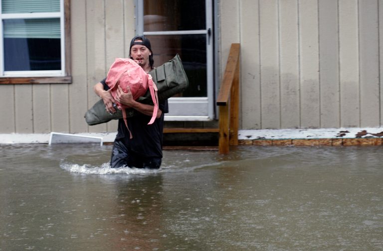 A man carries belongings through floodwaters from a home in Bridgewater, Vermont, on Monday, July 10, 2023. Heavy rain drenched part of the Northeast, washing out roads, forcing evacuations, and halting some airline travel.