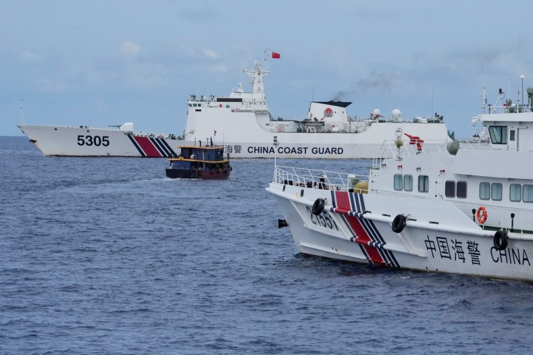 A Philippine supply boat, center, maneuvers around Chinese coast guard ships as they tried to block its way near Second Thomas Shoal, locally known as Ayungin Shoal, at the disputed South China Sea on Aug. 22, 2023.