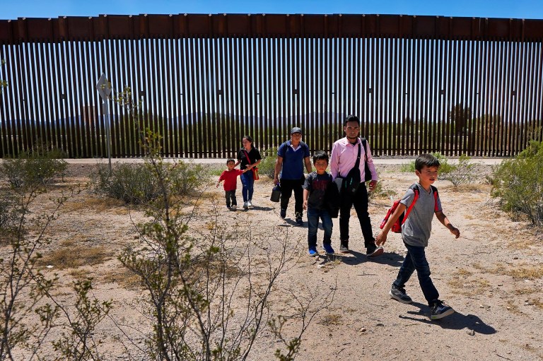 A family of five claiming to be from Guatemala and a man stating he was from Peru, in pink shirt, walk through the desert after crossing the border wall in the Tucson Sector of the U.S.-Mexico border, Tuesday, Aug. 29, 2023, in Organ Pipe Cactus National Monument near Lukeville, Arizona. 