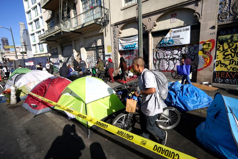 People line up along temporary tents to partake in a free Thanksgiving meal provided by the Union Rescue Mission as the Los Angeles Skid Row district annual feast hosts thousands of homeless and others in need, in downtown Los Angeles on Nov. 24, 2022. A Sacramento prosecutor is suing Californiaâs capital city over failure to clean up homeless encampments. Sacramento District Attorney Thien Ho announced the suit Tuesday, Sept. 19, 2023, during a news conference in Sacramento.
