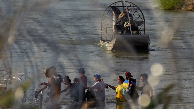 Border Patrol agents watch as migrants cross the Rio Grande from Mexico into the U.S. on Friday, Sept. 22, 2023, in Eagle Pass, Texas. 