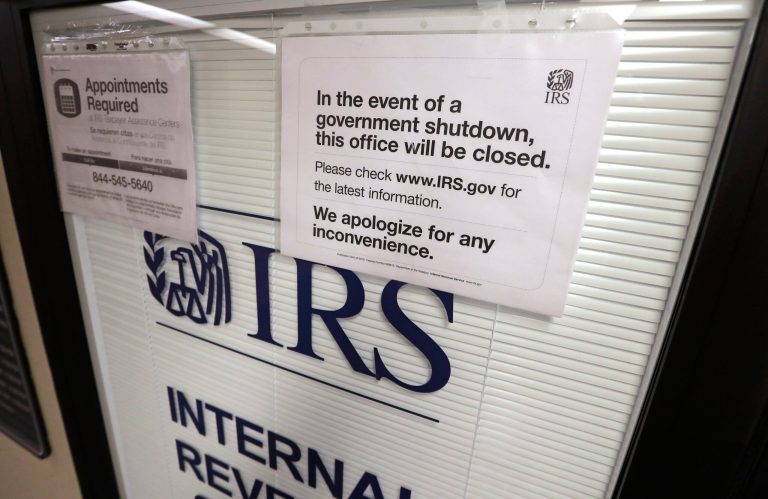 FILE - Doors at the Internal Revenue Service (IRS) in the Henry M. Jackson Federal Building are locked and covered with blinds as a sign posted advises that the office will be closed during the partial government shutdown Jan. 16, 2019, in Seattle. The federal government is heading toward a shutdown at month's end that will disrupt many services, squeeze workers and roil politics. (AP Photo/Elaine Thompson, File)