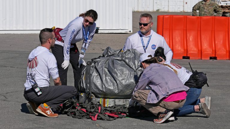 Recovery team members examine a capsule containing NASA's first asteroid samples before it is taken to a temporary clean room at Dugway Proving Ground in Utah on Sunday, Sept. 24, 2023. The Osiris-Rex spacecraft released the capsule following a seven-year journey to asteroid Bennu and back. 