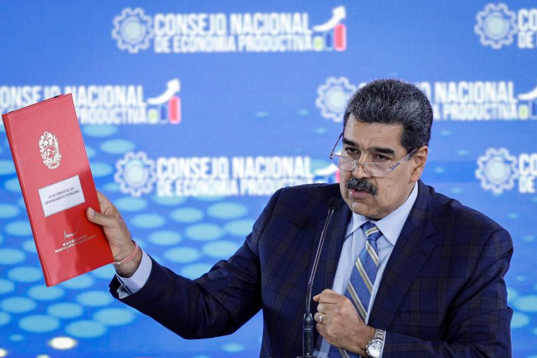Venezuelan President Nicolas Maduro shows a folder containing a proposed law to promote non-oil exports at a press conference.