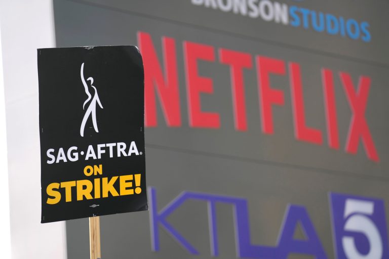 A picketer carries a sign on the picket line outside Netflix on Wednesday, Sept. 27, 2023, in Los Angeles. The actors' strike continues in their bid to get better pay and working conditions.