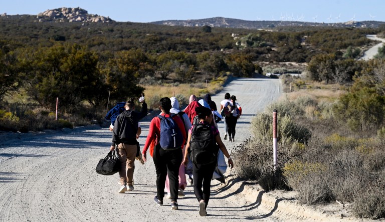 Asylum-seekers walk to a U.S. Border Patrol van after crossing the nearby border with Mexico, Tuesday Sept. 26, 2023, near Jacumba Hot Springs, California. Migrants continue to arrive at desert campsites along California's border with Mexico, as they await processing.