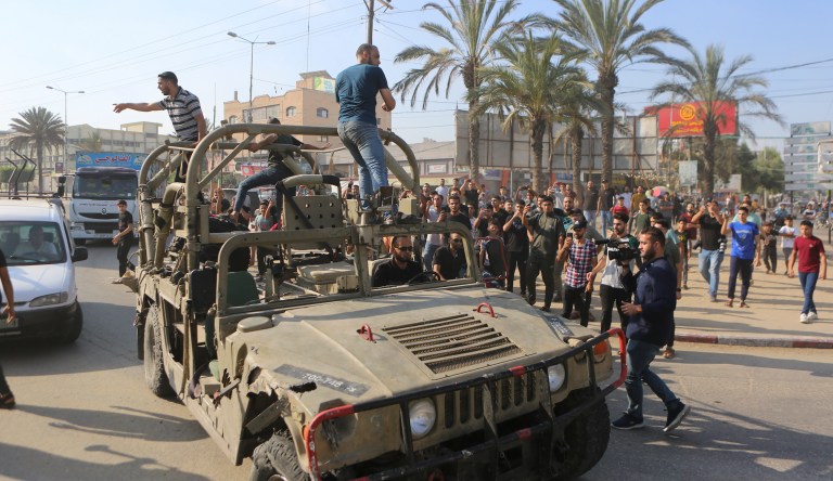 Palestinians ride on an Israeli military vehicle taken by an army base overrun by Hamas militants near the Gaza Strip fence, in Gaza City, Saturday, Oct. 7, 2023.