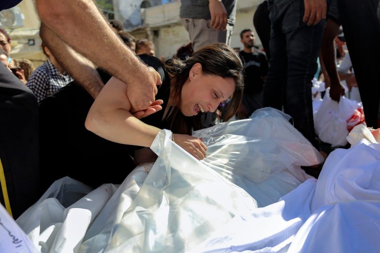 A Palestinian woman mourns over the bodies of her relatives who were killed in Israeli airstrikes that hit a Greek Orthodox church in Gaza City, Friday, Oct. 20, 2023. 