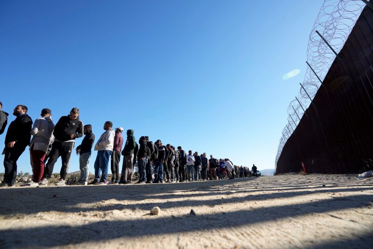 Men line up to receive food from volunteers with Border Kindness after crossing the border with Mexico Tuesday, Oct. 24, 2023, near Jacumba, California.